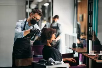 Black woman having a haircut at hairdressers during coronavirus pandemic.