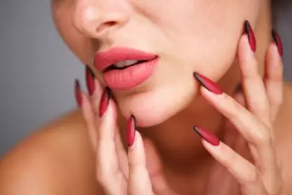 partial portrait of woman with red manicure and flawless complexion
